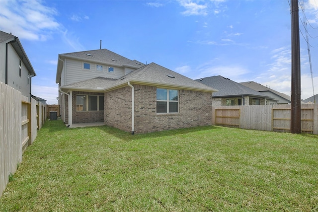 back of property with central AC unit and a yard