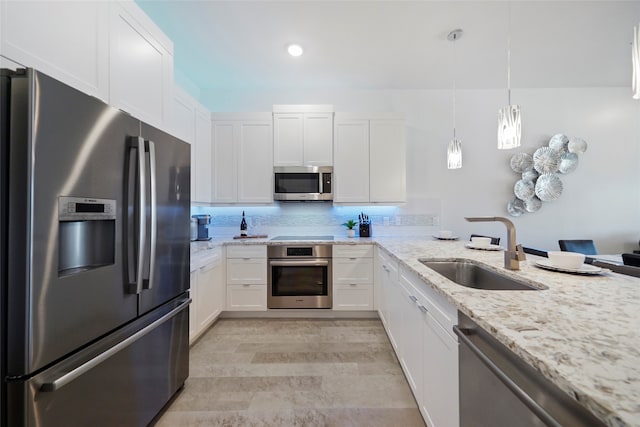 kitchen with white cabinetry, stainless steel appliances, decorative backsplash, sink, and light stone counters