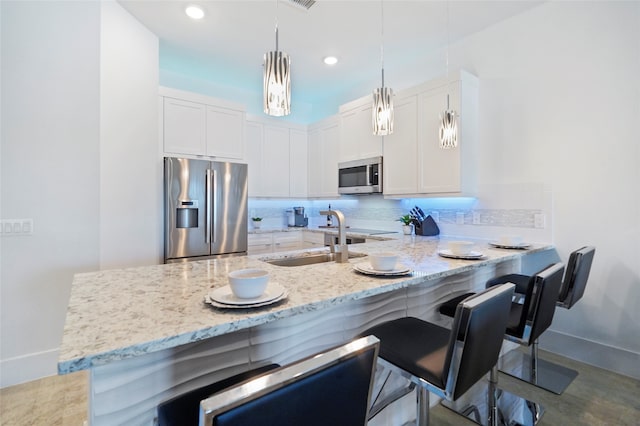 kitchen featuring appliances with stainless steel finishes, tasteful backsplash, white cabinets, sink, and light stone counters