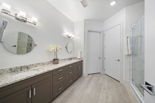 bathroom with walk in shower, wood-type flooring, and dual bowl vanity