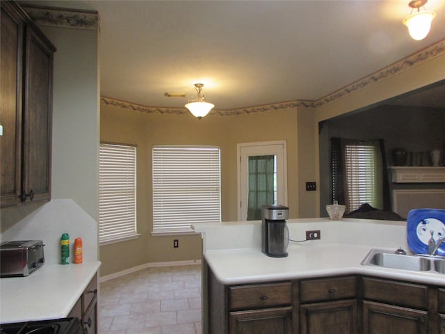 kitchen with light tile patterned flooring, sink, kitchen peninsula, and dark brown cabinetry