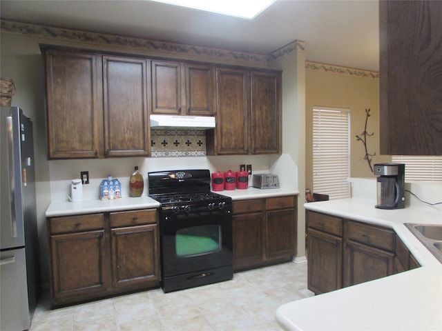 kitchen with black gas range, dark brown cabinetry, and stainless steel fridge