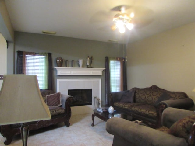 tiled living room featuring a tiled fireplace and ceiling fan