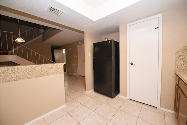 kitchen featuring black fridge, decorative light fixtures, and light tile patterned flooring