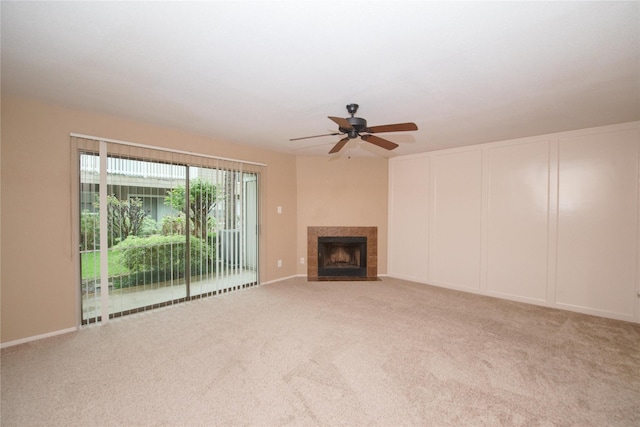 unfurnished living room with ceiling fan, a tile fireplace, and carpet