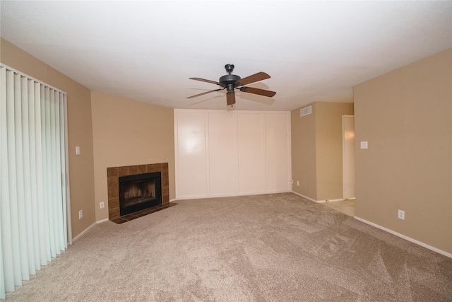 unfurnished living room featuring light carpet, a tiled fireplace, and ceiling fan