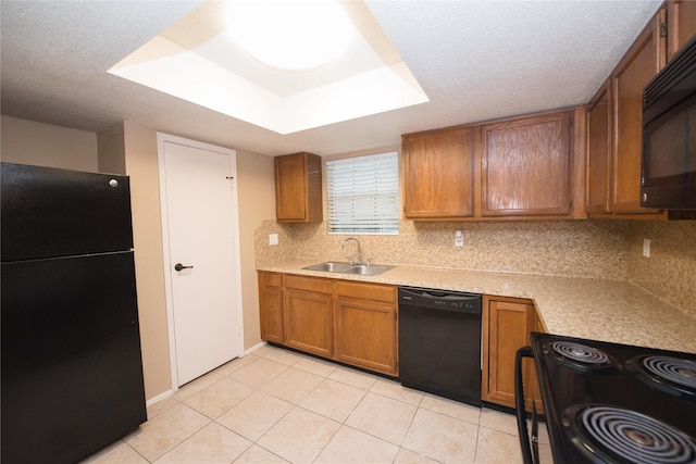 kitchen featuring sink, backsplash, a tray ceiling, black appliances, and light tile patterned flooring