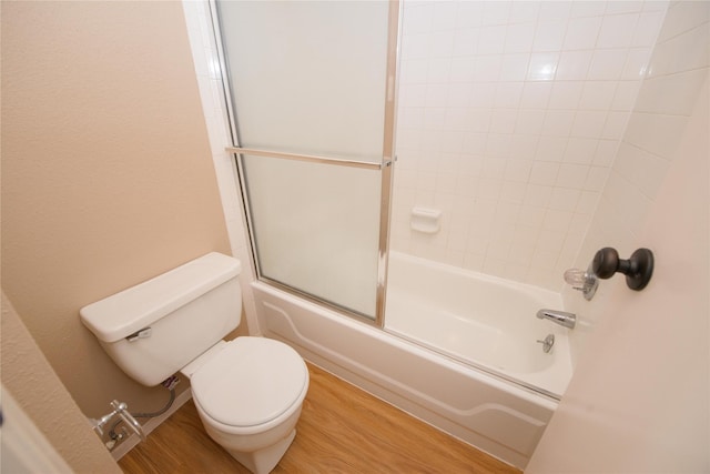 bathroom with hardwood / wood-style flooring, enclosed tub / shower combo, and toilet