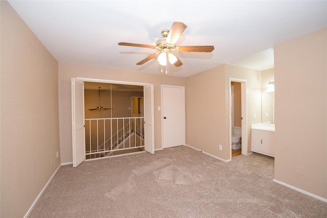 unfurnished bedroom featuring ceiling fan, connected bathroom, light colored carpet, and a closet