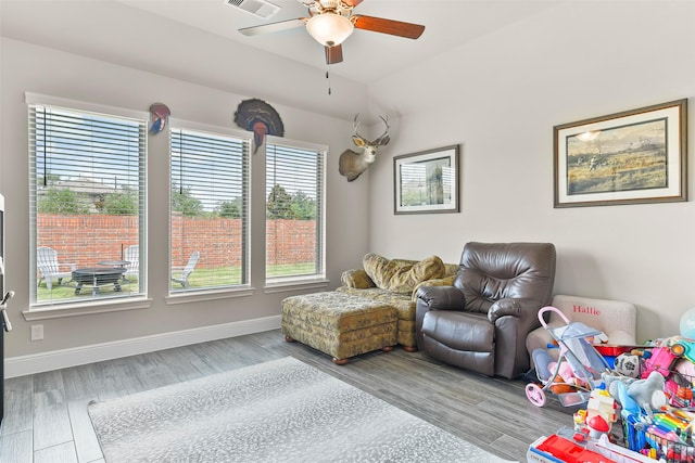 living area with light wood-type flooring, ceiling fan, and a healthy amount of sunlight