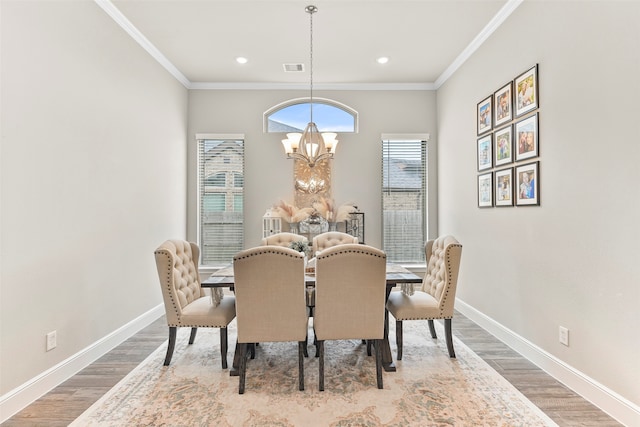 dining room with an inviting chandelier, crown molding, and hardwood / wood-style floors