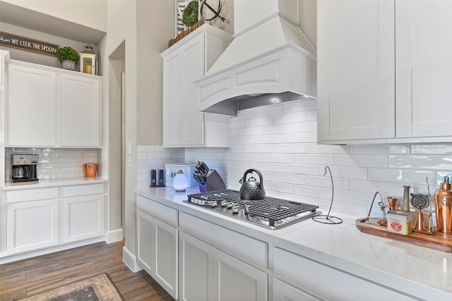 kitchen featuring dark hardwood / wood-style flooring, white cabinetry, tasteful backsplash, and custom exhaust hood