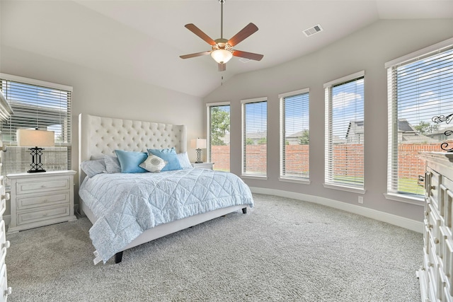 carpeted bedroom with multiple windows, ceiling fan, and vaulted ceiling