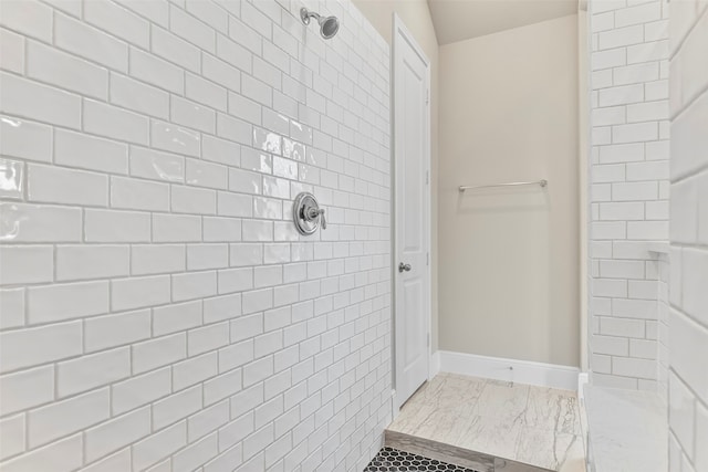 bathroom with a tile shower and tile patterned floors