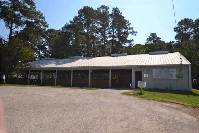 view of front of house featuring driveway, metal roof, and a front yard