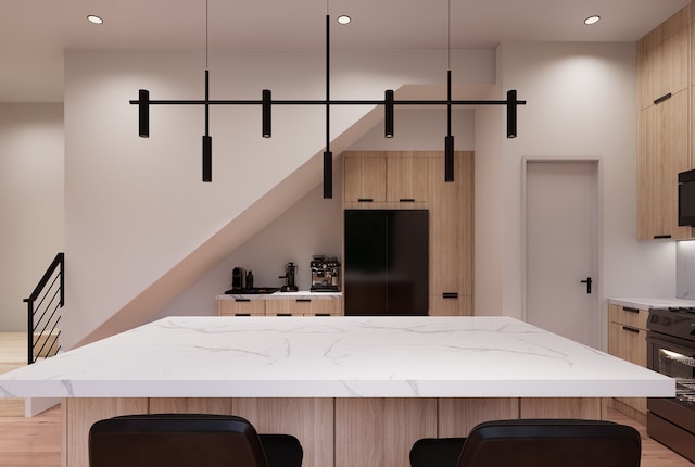 kitchen with black appliances, a kitchen island, a kitchen bar, and light wood-type flooring