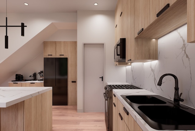 kitchen with light stone countertops, light brown cabinetry, light wood-type flooring, black appliances, and sink