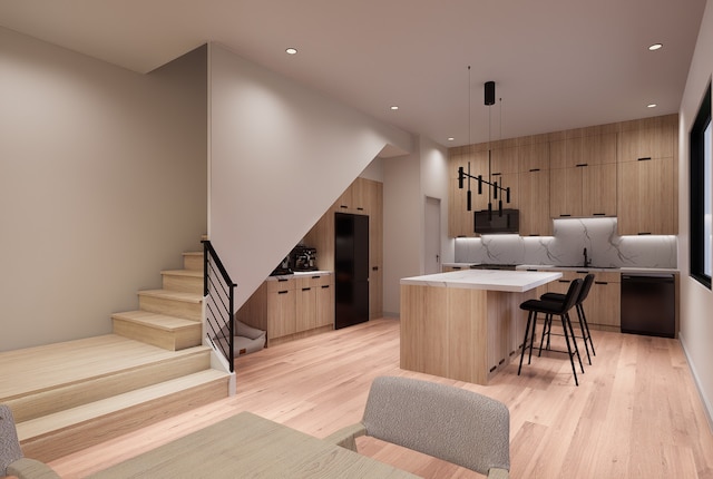 kitchen with a center island, black appliances, decorative light fixtures, and light wood-type flooring