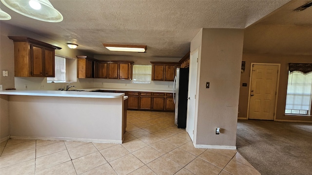 kitchen with plenty of natural light, stainless steel fridge, light tile patterned floors, and kitchen peninsula