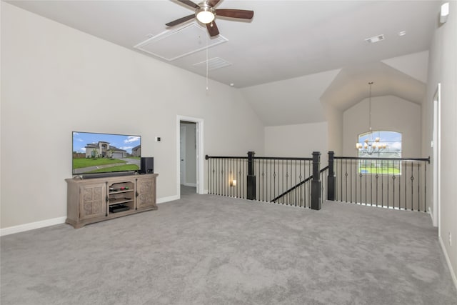 unfurnished living room with ceiling fan with notable chandelier, vaulted ceiling, and carpet