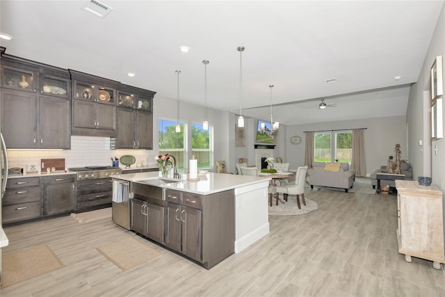 kitchen featuring tasteful backsplash, dark brown cabinetry, a kitchen island with sink, light wood-type flooring, and ceiling fan