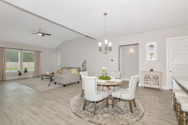 dining space featuring vaulted ceiling, ceiling fan with notable chandelier, and light hardwood / wood-style floors