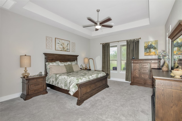 bedroom featuring light carpet, ceiling fan, and a raised ceiling