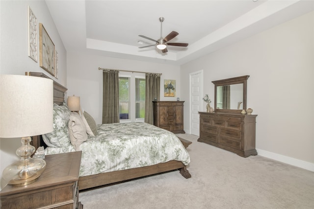 bedroom featuring ceiling fan, carpet, and a tray ceiling