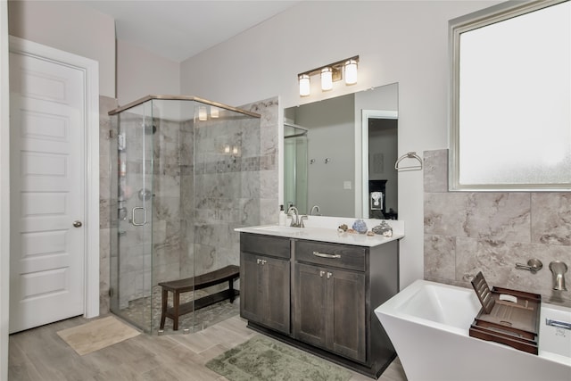 bathroom with vanity, separate shower and tub, hardwood / wood-style floors, and tile walls