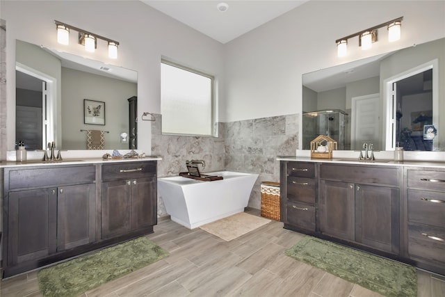 bathroom featuring tile walls, independent shower and bath, and dual bowl vanity