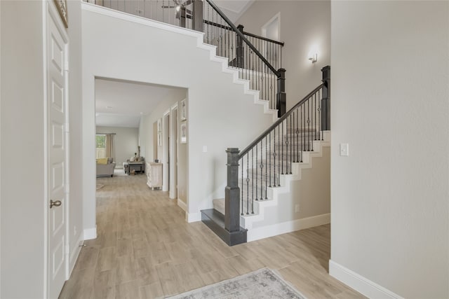 staircase featuring light hardwood / wood-style floors and a high ceiling