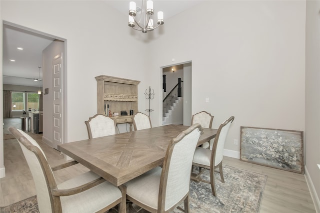 dining room featuring light hardwood / wood-style floors, a notable chandelier, and a high ceiling