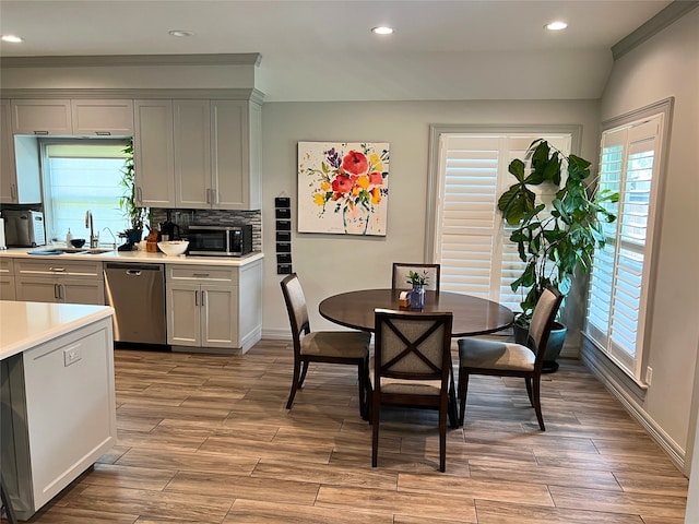 dining area with ornamental molding, sink, and light wood-type flooring