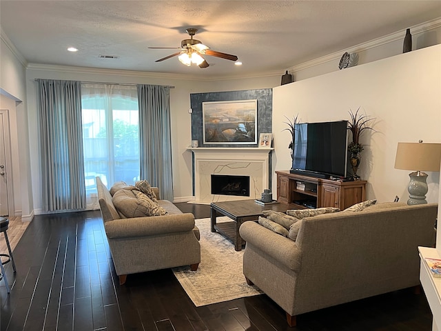 living room with a fireplace, crown molding, a textured ceiling, ceiling fan, and dark hardwood / wood-style floors