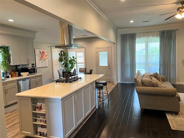 kitchen with a kitchen island, a breakfast bar area, dark wood-type flooring, stainless steel appliances, and ceiling fan