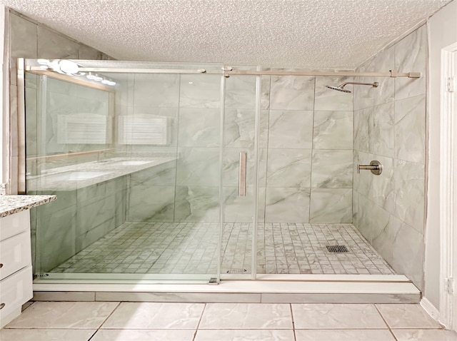 bathroom with tile patterned floors, a textured ceiling, a shower with door, and vanity