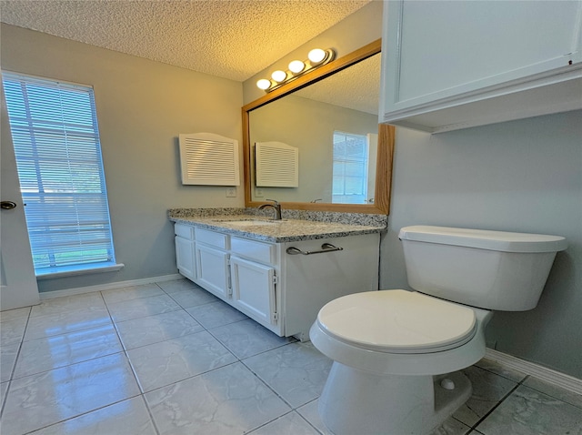 bathroom featuring vanity, toilet, a textured ceiling, and a wealth of natural light