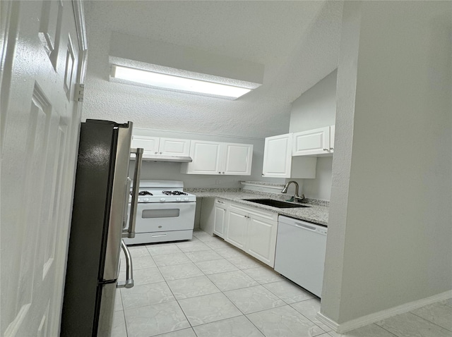 kitchen featuring a textured ceiling, sink, vaulted ceiling, white cabinetry, and white appliances