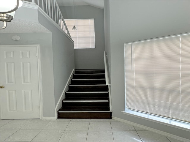 stairs featuring a notable chandelier, lofted ceiling, and tile patterned flooring