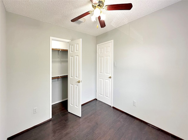 unfurnished bedroom with ceiling fan, a textured ceiling, a closet, and dark hardwood / wood-style flooring