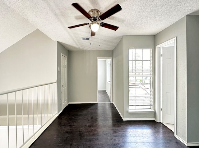 interior space with ceiling fan, a textured ceiling, and dark wood-type flooring