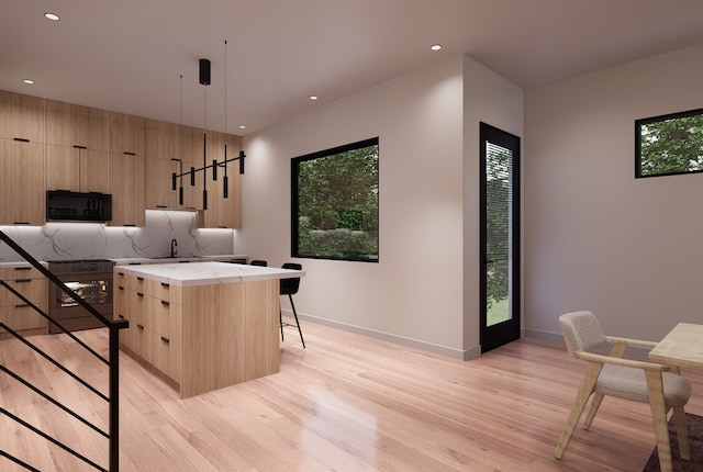 kitchen with a wealth of natural light, a center island, hanging light fixtures, and light hardwood / wood-style floors