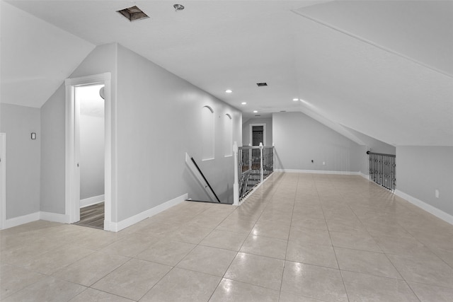 bonus room with light tile patterned floors and vaulted ceiling