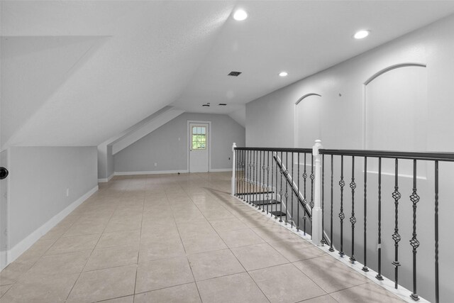 additional living space with vaulted ceiling and light tile patterned floors