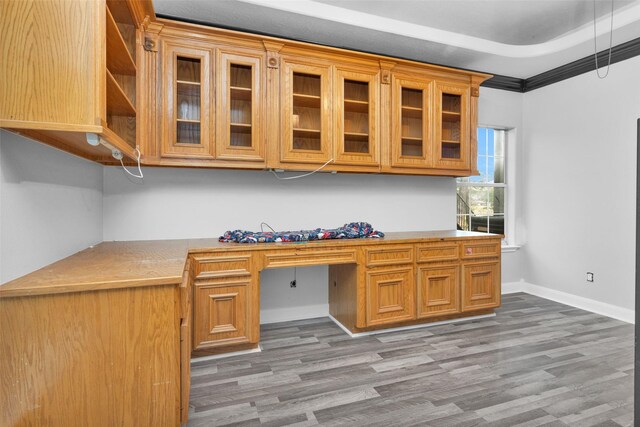 office area with crown molding, a tray ceiling, built in desk, and hardwood / wood-style floors