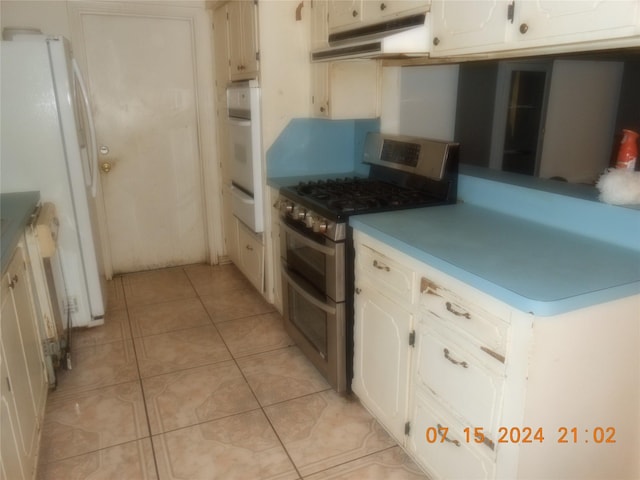 kitchen featuring white cabinets, light tile patterned flooring, and white appliances