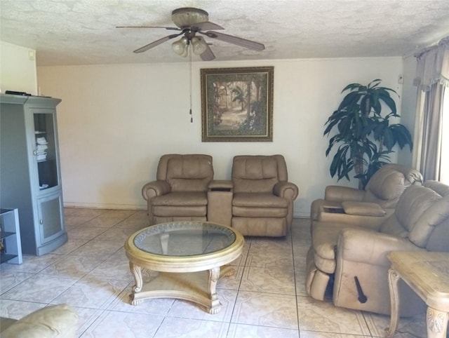 living room featuring ceiling fan, light tile patterned floors, and a textured ceiling