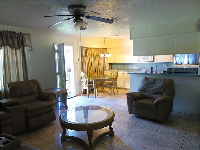 living room with tile patterned flooring, ceiling fan with notable chandelier, and a textured ceiling