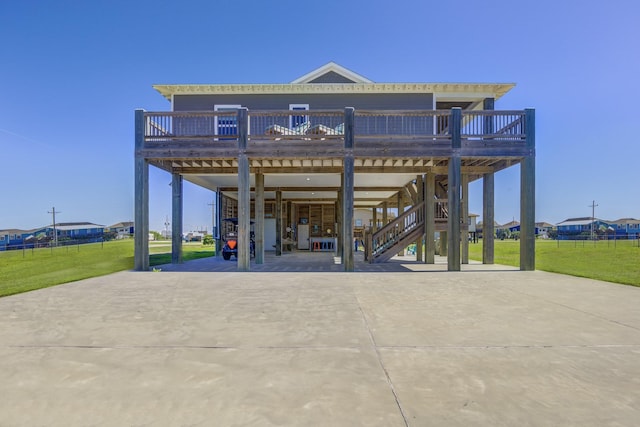 back of house with stairs, a carport, a yard, and concrete driveway