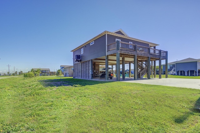 back of house with stairs, a lawn, a carport, and concrete driveway